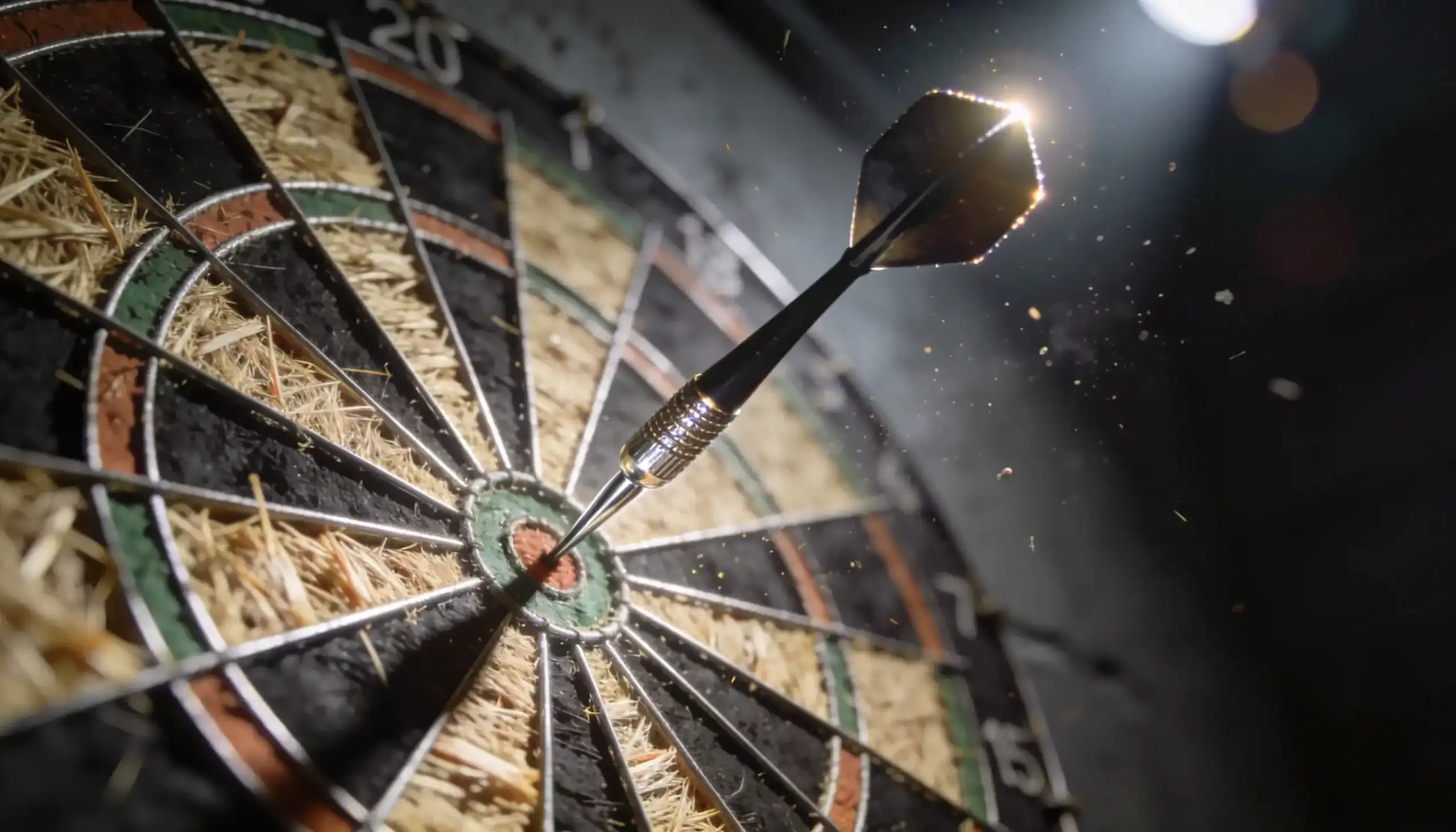 Dartpfeil trifft das Bullseye eines Dartboards auf einer beleuchteten Bühne